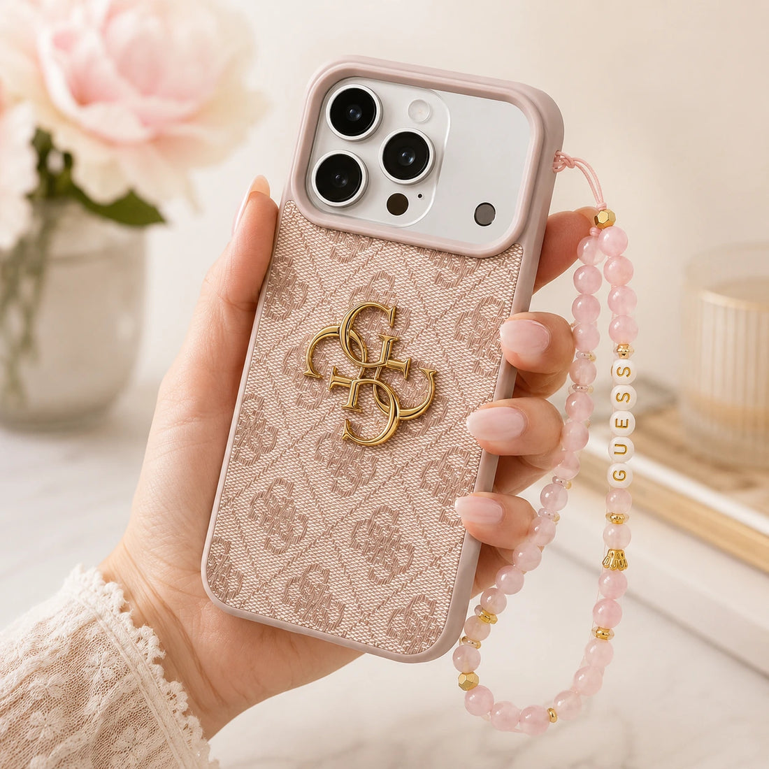 Coque Guess iPhone 17 Pro rose avec sangle portée en main