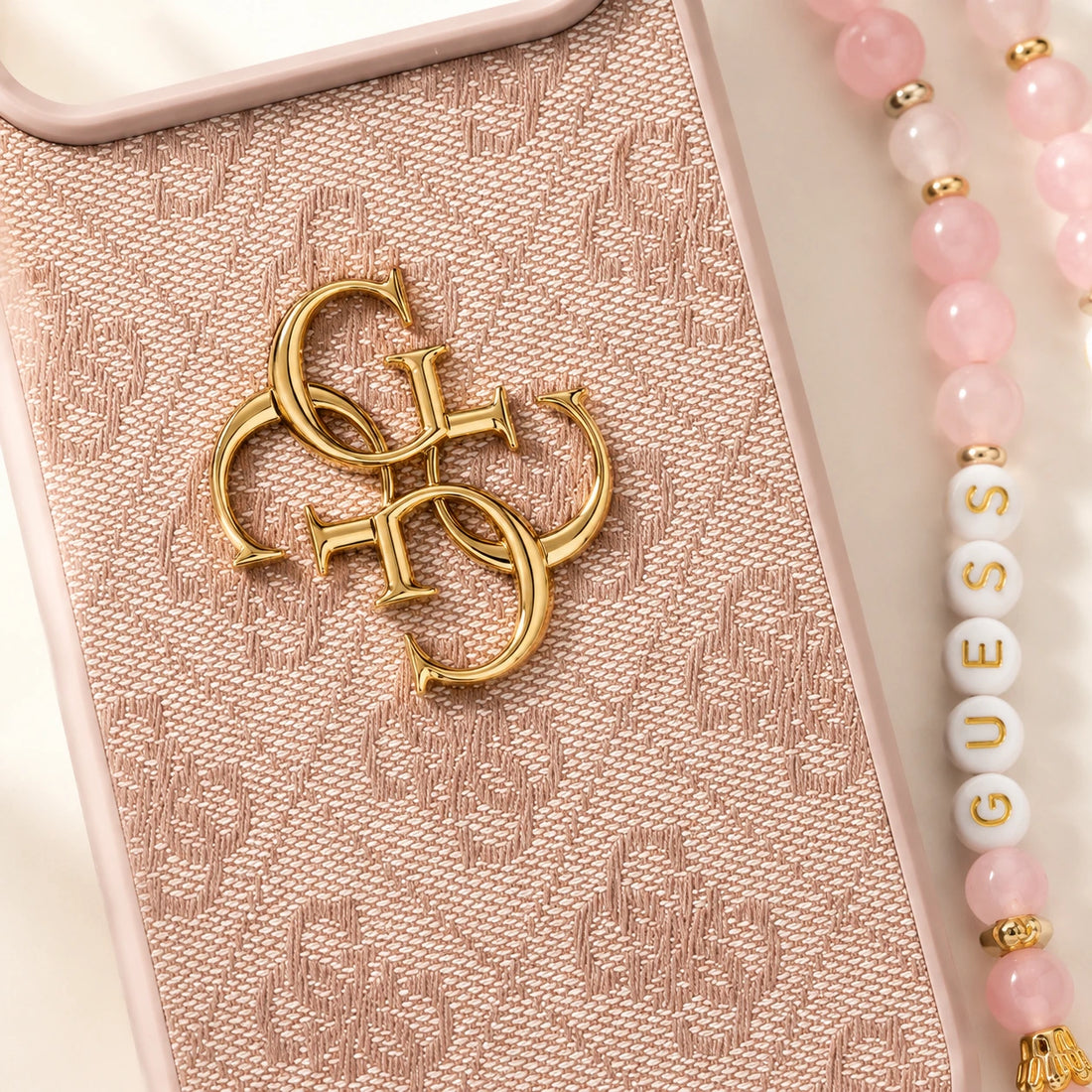 Gros plan coque Guess iPhone 17 Pro rose avec logo doré et motif 4G